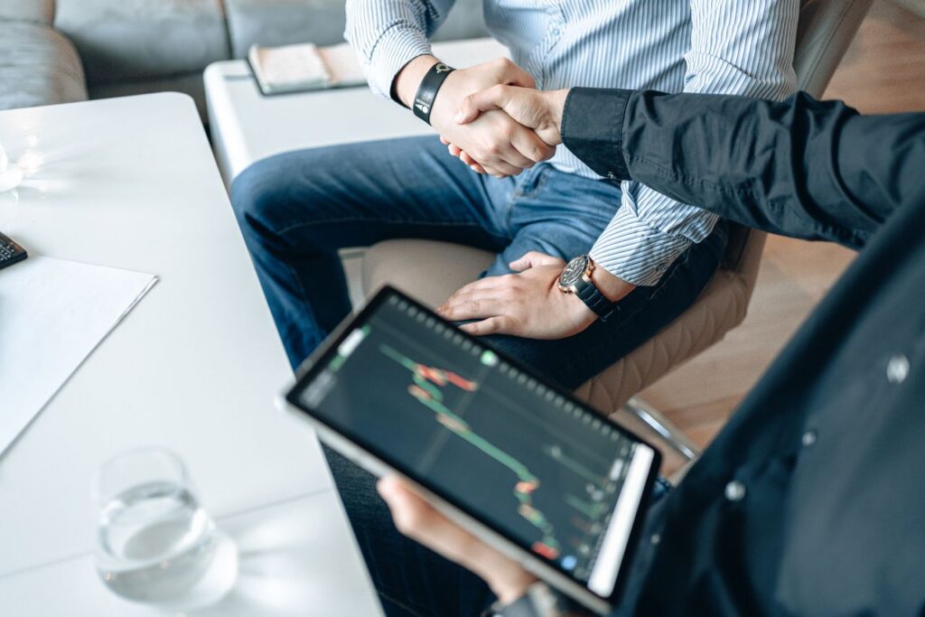 Crafting Captivating Headlines: Your awesome post title goes here Business professionals shaking hands with a tablet displaying financial graphs.