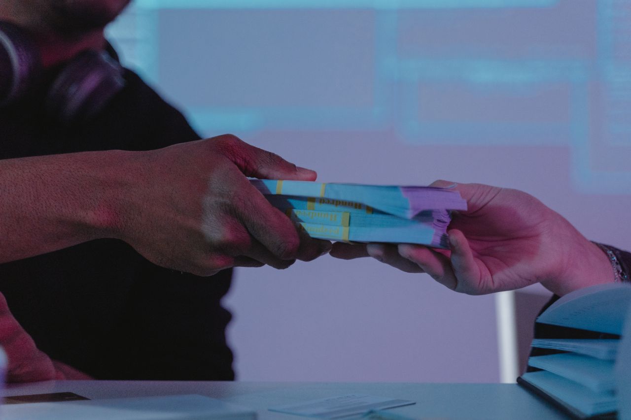 Mastering the First Impression: Your intriguing post title goes here Close-up of hands exchanging money, highlighting financial exchange in a dimly lit setting.