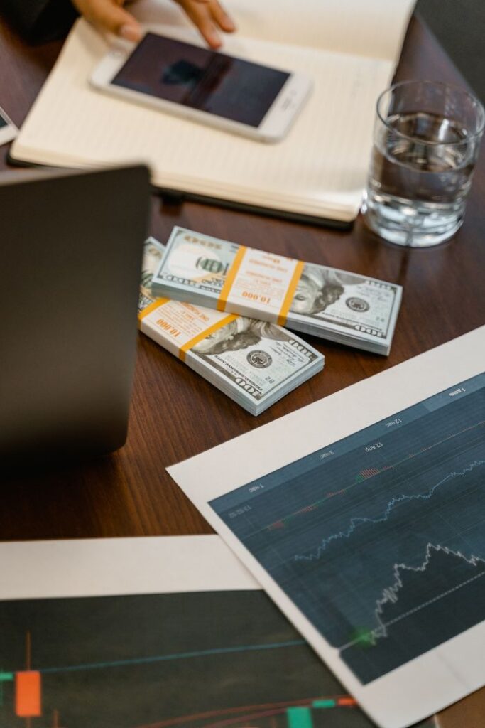 Stacks of US dollars and analytics charts on a wooden table, ideal for finance concepts.